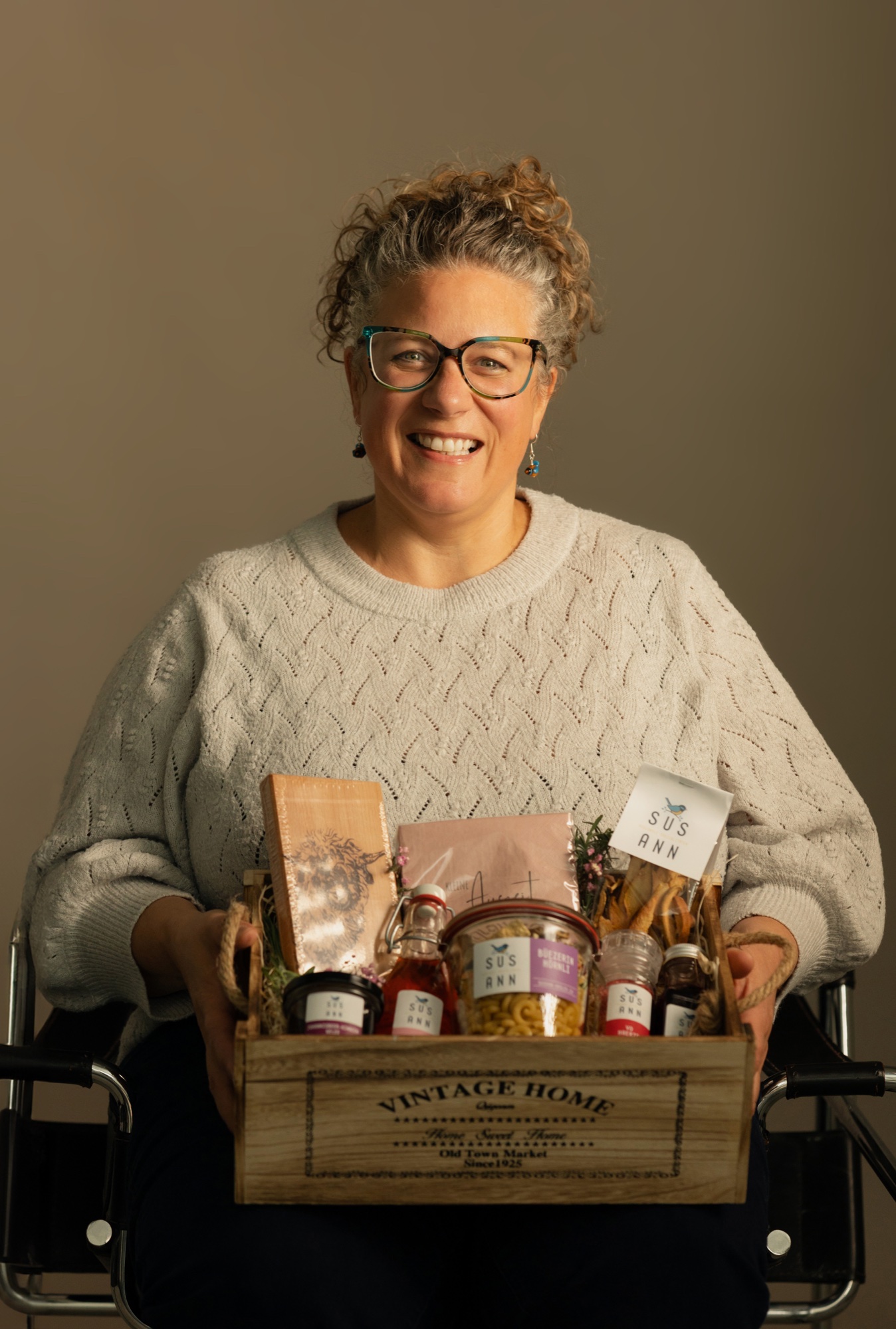 Susann Hasler sitzend mit einem Geschenkset in der Vintage-Holzkiste